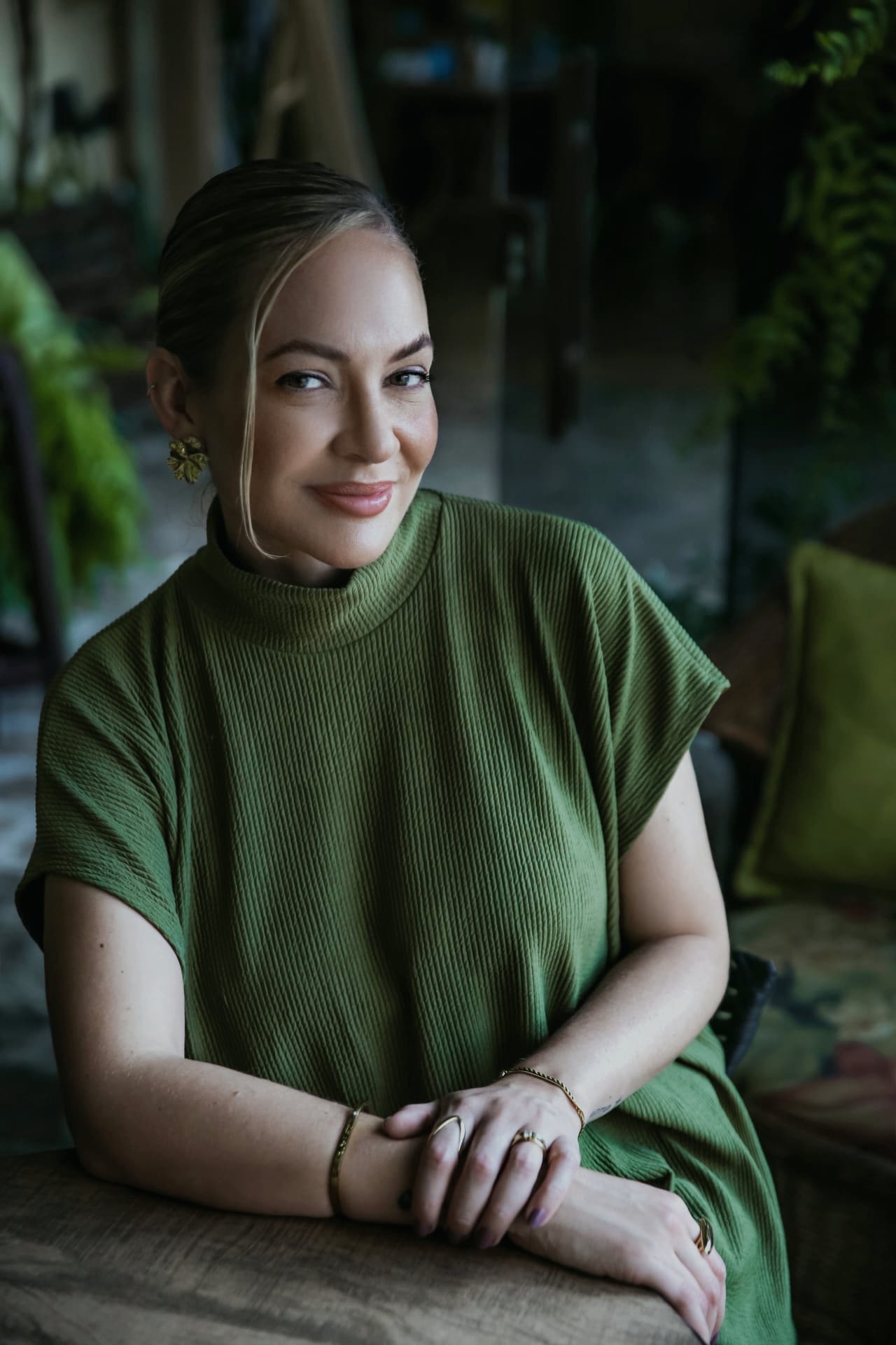 Dra. Maikiara sorrindo em meio às plantas da Aysú Clínica